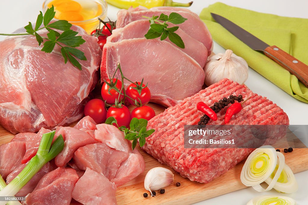 Different type of raw meat on a chopping board, garnished