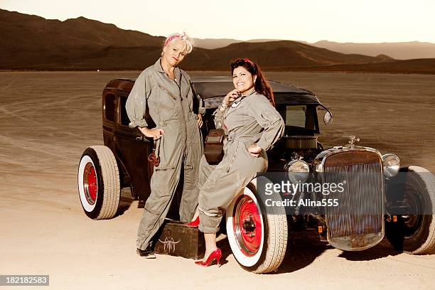 retro pinup girls in mechanic's coveralls by a classic car - 40s pin up girls stock pictures, royalty-free photos & images