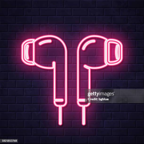 earphones. glowing neon icon on brick wall background - in ear headphones stock illustrations
