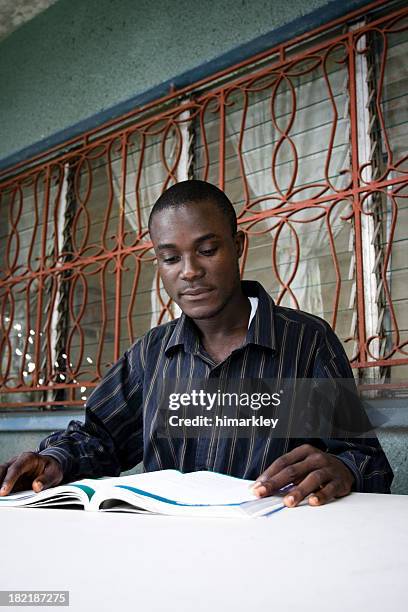 young man settled in to study from his open textbook - west africa stock pictures, royalty-free photos & images
