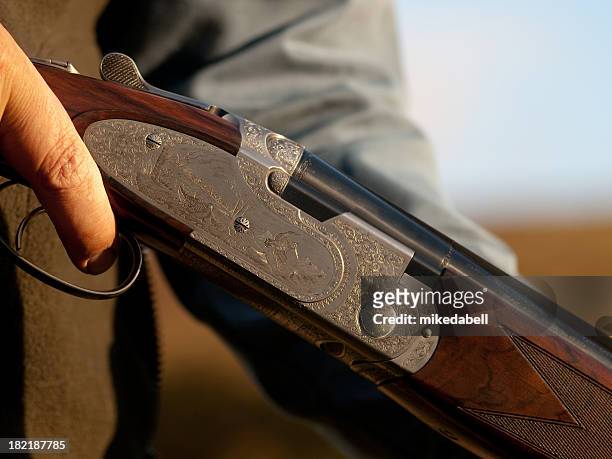 a close up of a man holding a shotgun - jachtgeweer stockfoto's en -beelden