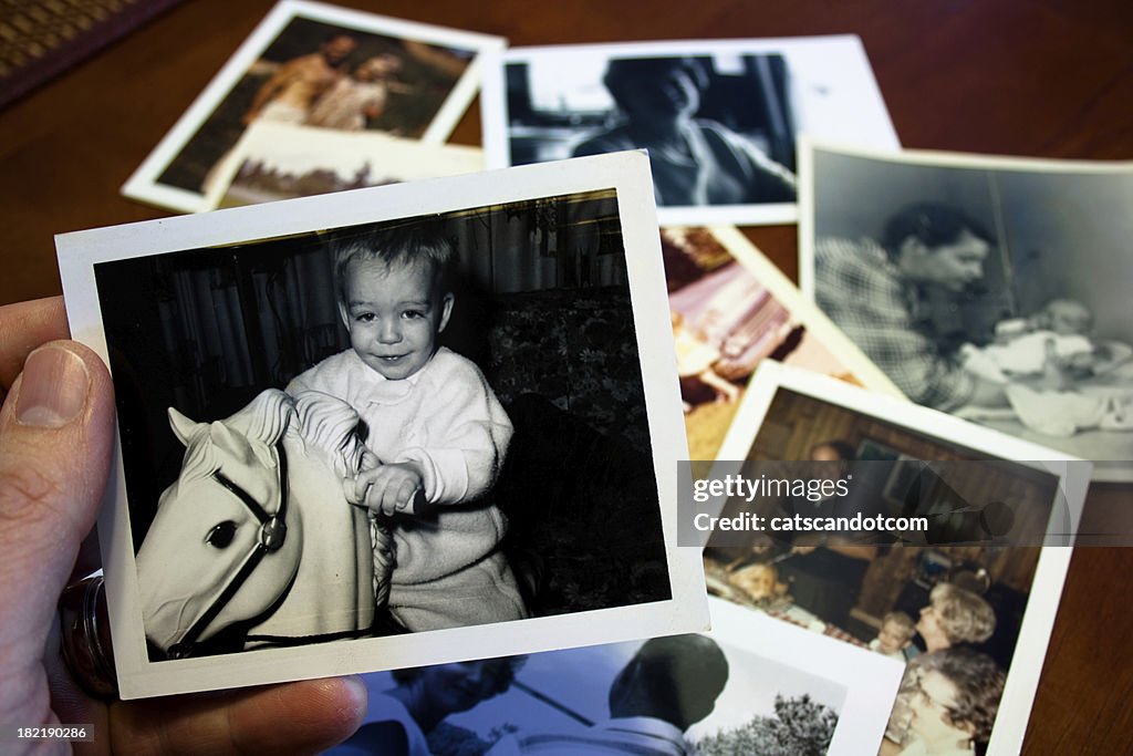 Hand holds Vintage photograph of child with hobby horse toy