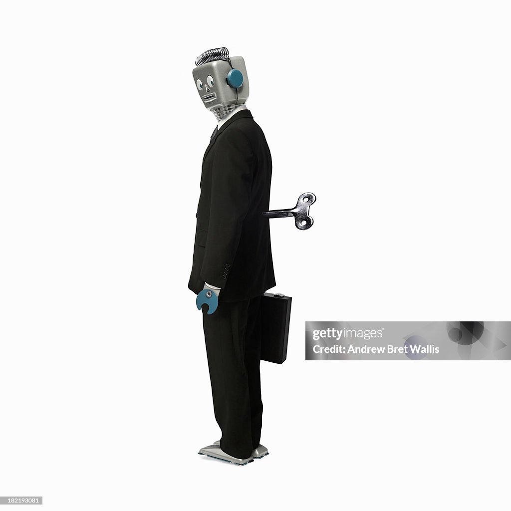 Robot businessman stands with a key in his back