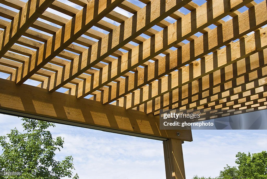 Cedar pergola with sky and trees in background
