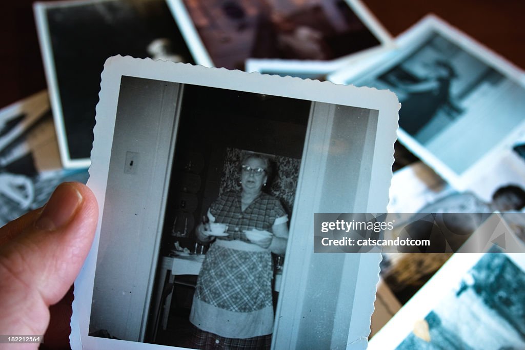 Hand holds Vintage photograph of 1950s grandma serving soup