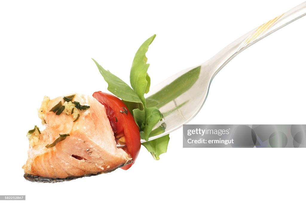 Isolated background of salmon, rucola and tomato on fork