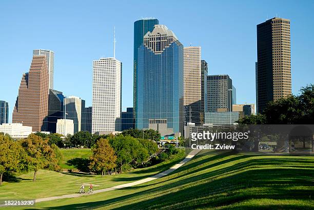 houston, texas skyline across park with cyclists - houston texas stock pictures, royalty-free photos & images