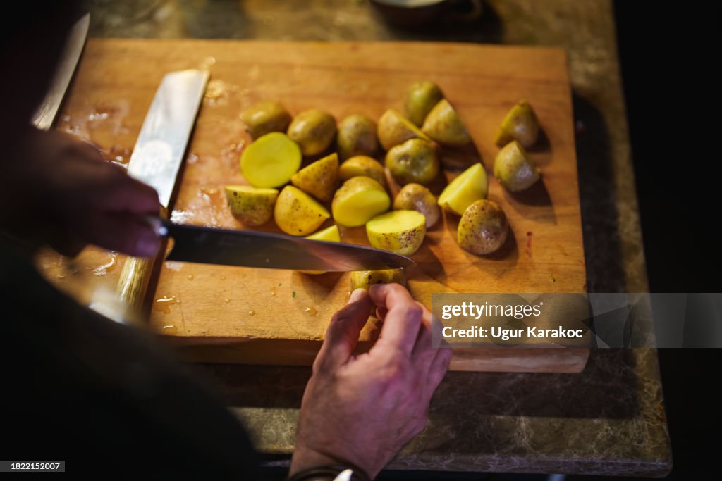 Mann schneidet Kartoffeln auf Schneidebrett mit Messer, kocht Abendessen