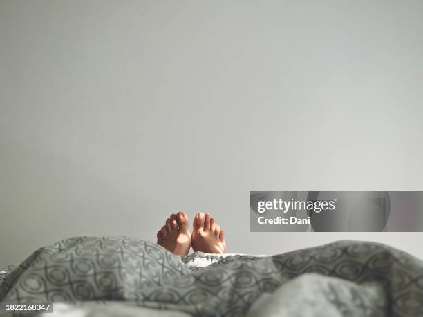close-up of a woman's feet sticking out of the end of a duvet in bed - personal perspective or pov stock pictures, royalty-free photos & images