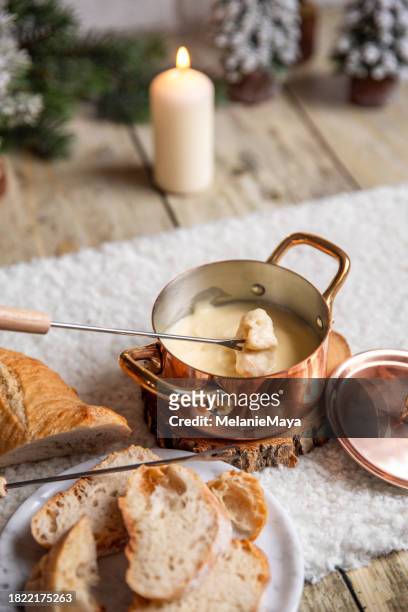 eating swiss cheese fondue with rosé wine at cozy winter kitchen with christmas decorations - cheese fondue stock pictures, royalty-free photos & images