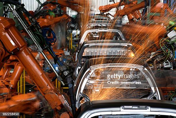 roboter in einer autofabrik - automobilbau stock-fotos und bilder