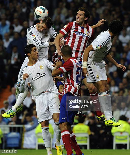 Real Madrid's spanish defender and captain Sergio Ramos vies with Atletico Madrid's Uruguayan defender Diego Godin past Real Madrid's Portuguese...