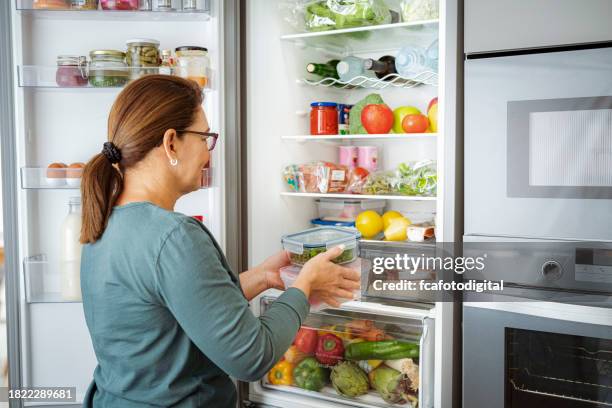 woman takes containers with raw food from fridge - frigorífico imagens e fotografias de stock