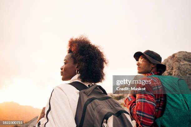 young male and female backpacker looking away on vacation - senderismo fotografías e imágenes de stock