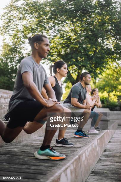 focused male and female friends practicing lunges on steps - affondo foto e immagini stock