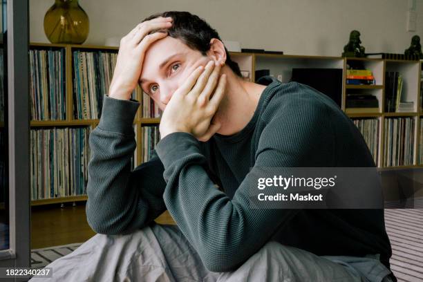 depressed young man looking away while sitting at home - anxiety stock pictures, royalty-free photos & images