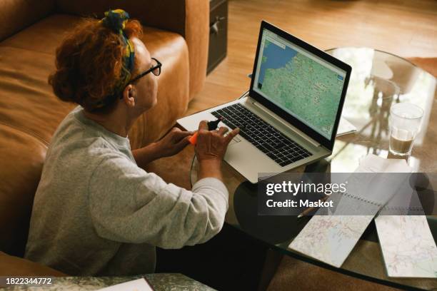 side view of elderly woman planning trip on map in laptop at home - book icon stock pictures, royalty-free photos & images