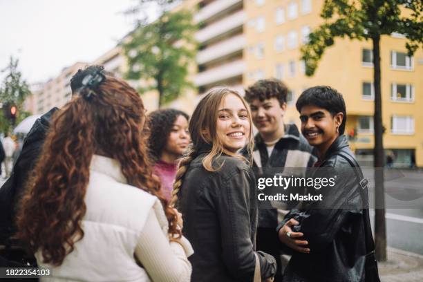 portrait of smiling girl standing with male and female friends at street - männlicher teenager stock-fotos und bilder