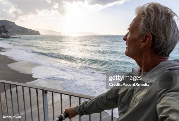 mature man watches sunrise over sea and hills - harmony stock pictures, royalty-free photos & images