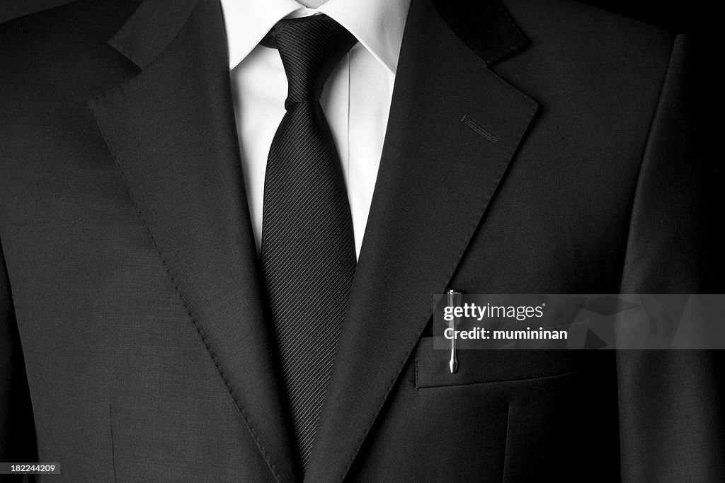 Black business suit and tie with a white shirt and a pen