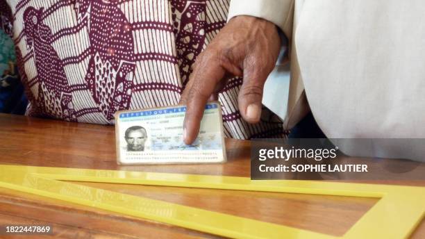 Un homme tient sa carte d'identité avant de pouvoir s'enregistrer pour voter, le 20 mars 2011 dans un bureau de vote de Koungou, à 15 km au nord du...