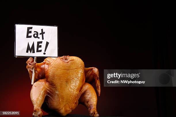 a headless cooked turkey holding a sign that says eat me  - funny rooster stockfoto's en -beelden