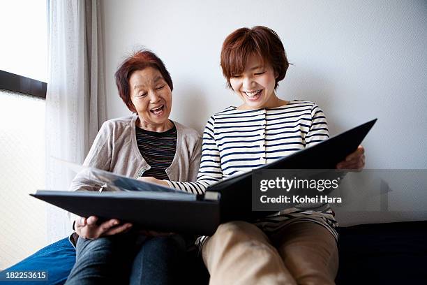 mother and daughter looking a photo album - leanincollection mother stock pictures, royalty-free photos & images