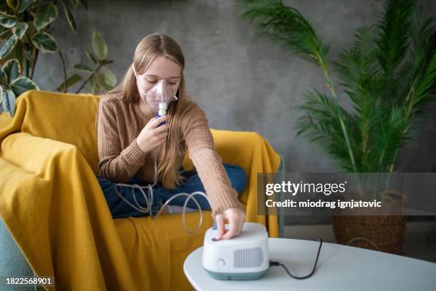 girl using a portable nebulizer at home - nebulizer stock pictures, royalty-free photos & images