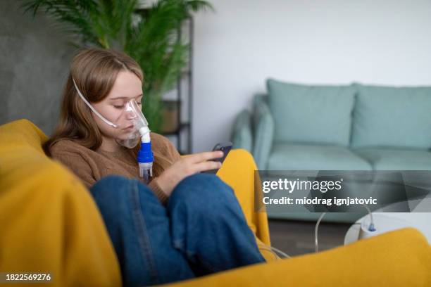 girl using a portable nebulizer at home - nebulizer stock pictures, royalty-free photos & images