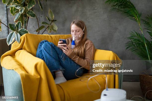 girl using a portable nebulizer at home - nebulizer stock pictures, royalty-free photos & images