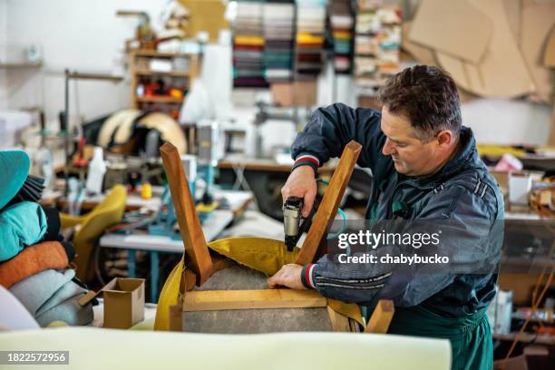 craftsperson upholsters furniture in factory - upholstry stockfoto's en -beelden
