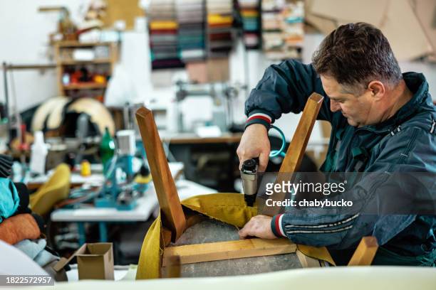 techniker arbeitet mit tacker in möbelwerkstatt - upholstered chair stock-fotos und bilder