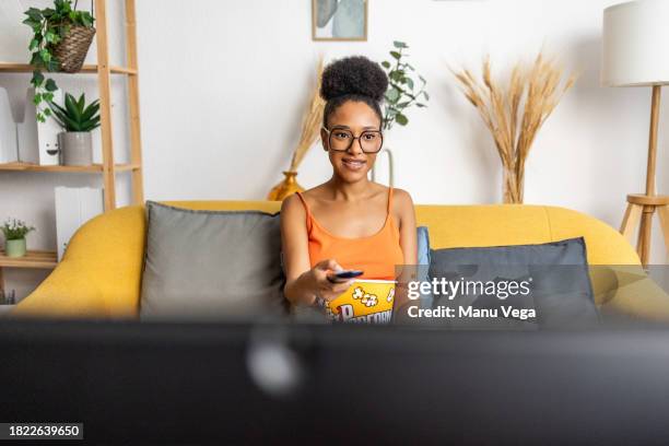 happy black woman using tv remote while resting on sofa - alpha channel stock pictures, royalty-free photos & images