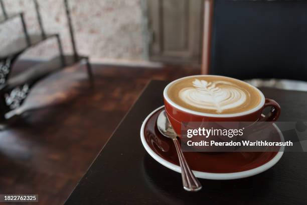 cappuccino on top with beautiful delicate latte art with leaf pattern, and background of red rough rusty metal table. - coffee top view stock-fotos und bilder