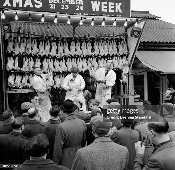 Crowd of people watch fresh turkeys hanging on display during an auction at Smithfield Meat Market, London, December 21st 1957.