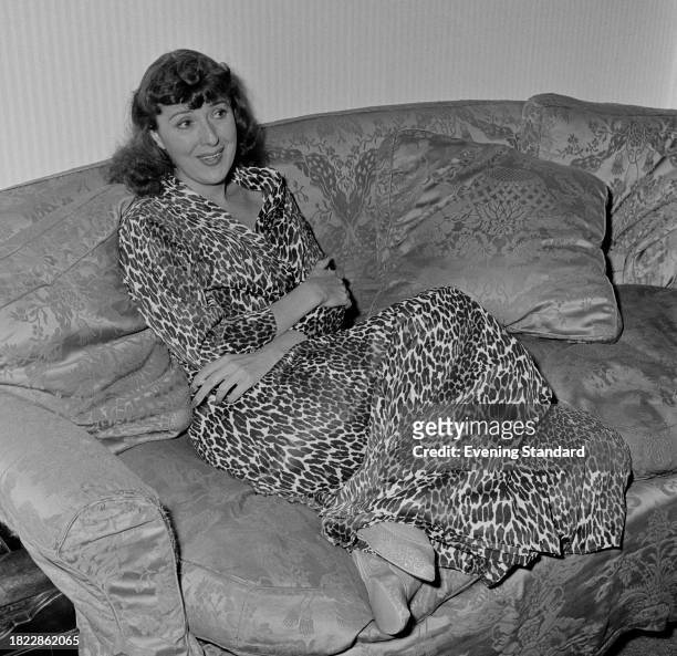 Burlesque dancer, actress and author Gypsy Rose Lee , reclining on a sofa, October 1st 1957.