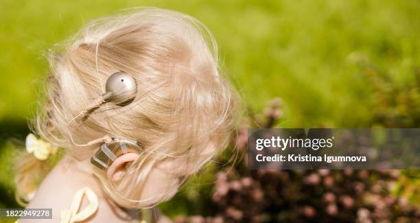 funny baby with cochlear implant walking. hear aid and medicine innovating technology and diversity concept. copy space banner - cochlea implant stock pictures, royalty-free photos & images