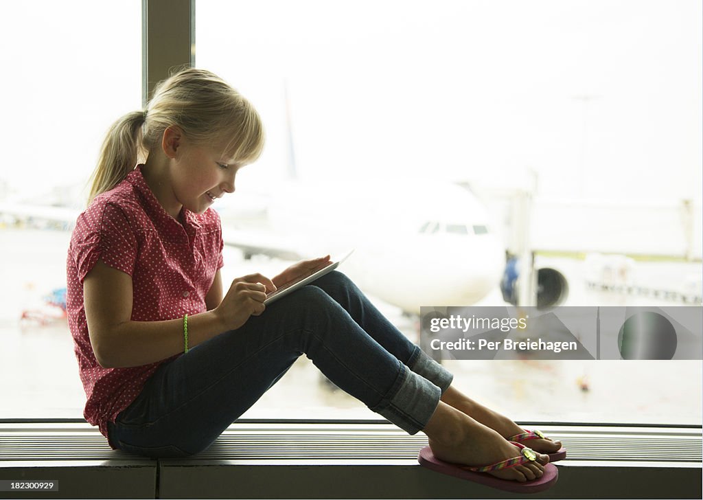 A girl looking at her tablet computer at the airport