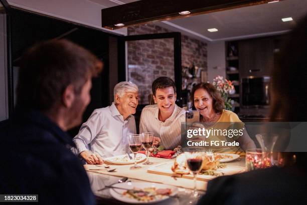 petit-enfant prenant un soi avec ses grands-parents au dîner de noël - réunion de famille photos et images de collection
