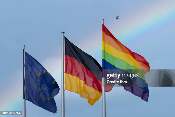 eu-, german- and rainbow(lgbtq+)- flag with rainbow in the sky - berlin gay pride stock pictures, royalty-free photos & images