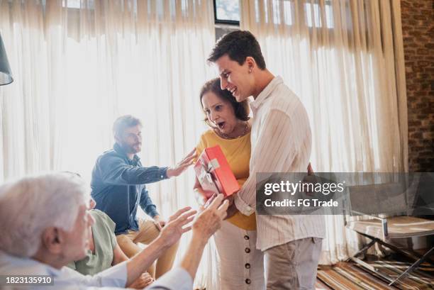 grandson embracing his grandmother after giving her a christmas present n at home - hug christmas stock pictures, royalty-free photos & images