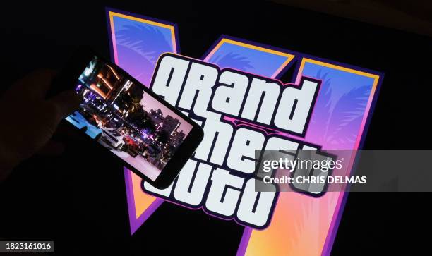 This illustration photo created in Los Angeles, December 4 shows Rockstar Games' Grand Theft Auto VI trailer played on a screen in front of the game...