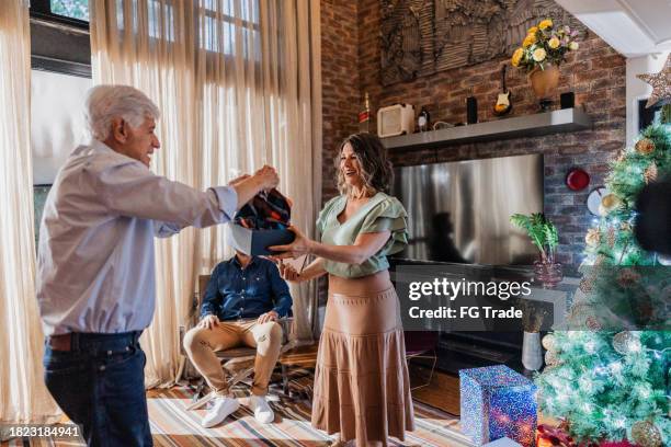mujer madura dando un regalo a su padre en navidad - amigo invisible fotografías e imágenes de stock