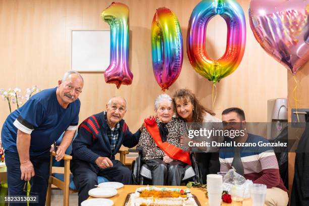 centenarian celebration. 100 year old woman in the company of her sons, daughter, and grandson during her 100th birtday posing for a family photo - centennial 100 celebration stock-fotos und bilder