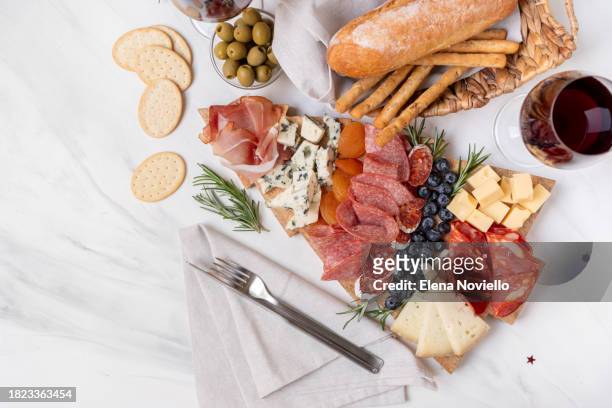 charcuterie board italian food antipasti prosciutto ham, salami and cheese appetizers served in the shape of a christmas tree. festive aperitif or party two glasses of champagne, prosecco or rosé wine. party food for new year's eve and christmas - snag tree stock pictures, royalty-free photos & images