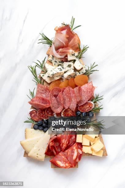 charcuterie board italian food antipasti prosciutto ham, salami and cheese appetizers served in the shape of a christmas tree. festive aperitif or party two glasses of champagne, prosecco or rosé wine. party food for new year's eve and christmas - snag tree stock pictures, royalty-free photos & images