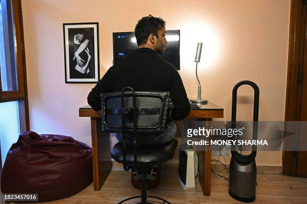 In this picture taken on December 1 independent cinematographer Madhav Mathur sits beside an air purifier as he works from home in New Delhi....