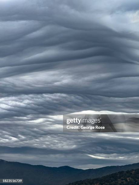 Unusual asperitas clouds, created by a strong jetstream rushing overhead and hitting the nearby mountains, above a tranquil Danish tourist town as...