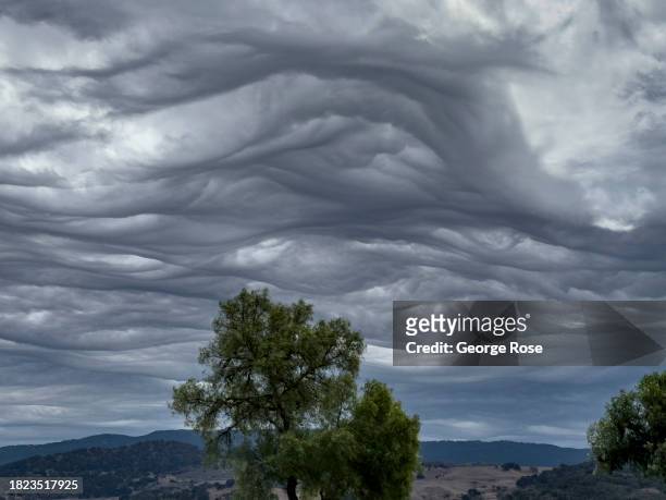 Unusual asperitas clouds, created by a strong jetstream rushing overhead and hitting the nearby mountains, above a tranquil Danish tourist town as...
