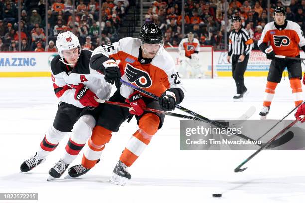 Jack Hughes of the New Jersey Devils and Ryan Poehling of the Philadelphia Flyers challenge for the puck during the second period at the Wells Fargo...